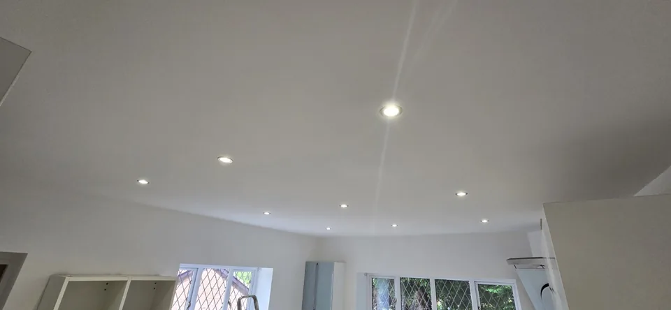 Reinstated white kitchen ceiling in Altrincham with recessed lights switched on.