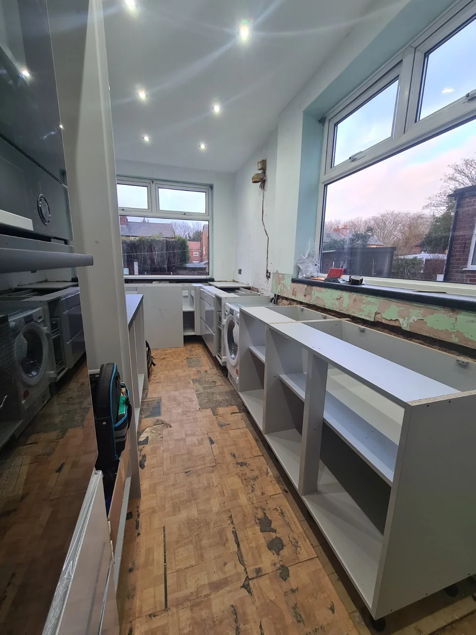 New kitchen base units being fitted along the window wall near Burnage.