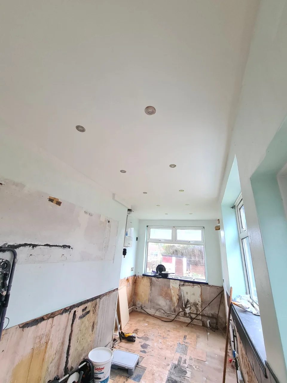 The smooth white kitchen ceiling and recessed light fittings during the Burnage refurbishment.