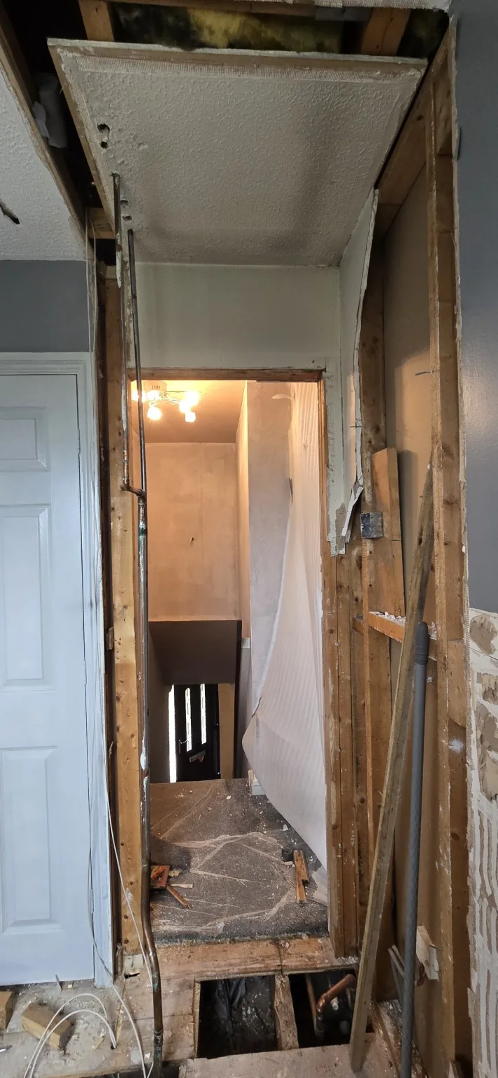 The former tank cupboard during removal, showing exposed framing, ceiling edges and floor openings.