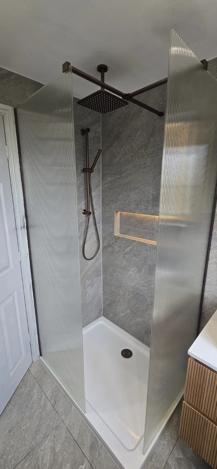 New separate shower enclosure with ribbed glass screens, overhead shower and an illuminated wall niche.