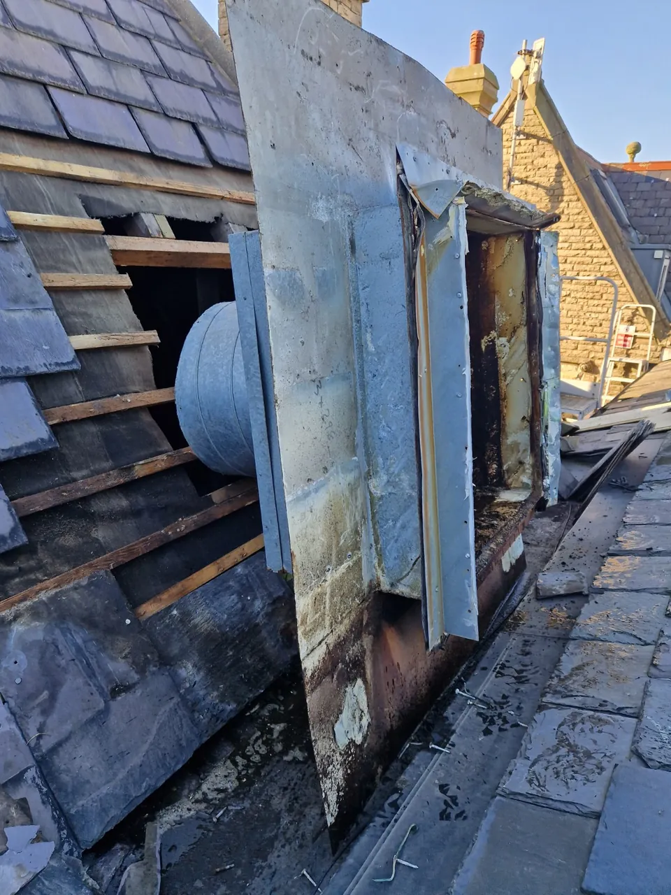 Extractor assembly pulled away from the roof, with the surrounding slates removed and battens exposed.