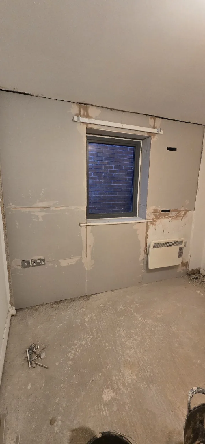 Replacement wall boards fitted around the bedroom window, with board joints and edges prepared.