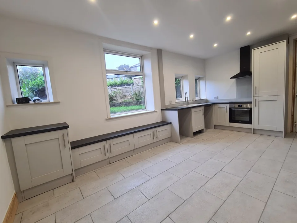 Wide view of the new Rawtenstall kitchen, with pale shaker-style cabinets, dark worktops and low storage beneath the window.