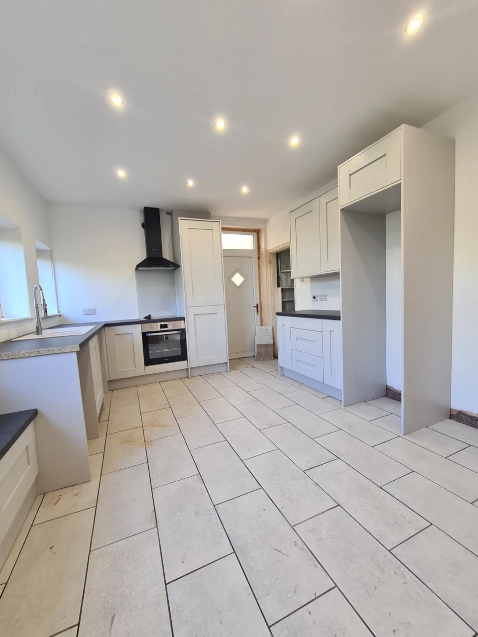 New pale shaker-style kitchen units, dark worktops and tiled flooring during fitting in Rawtenstall.