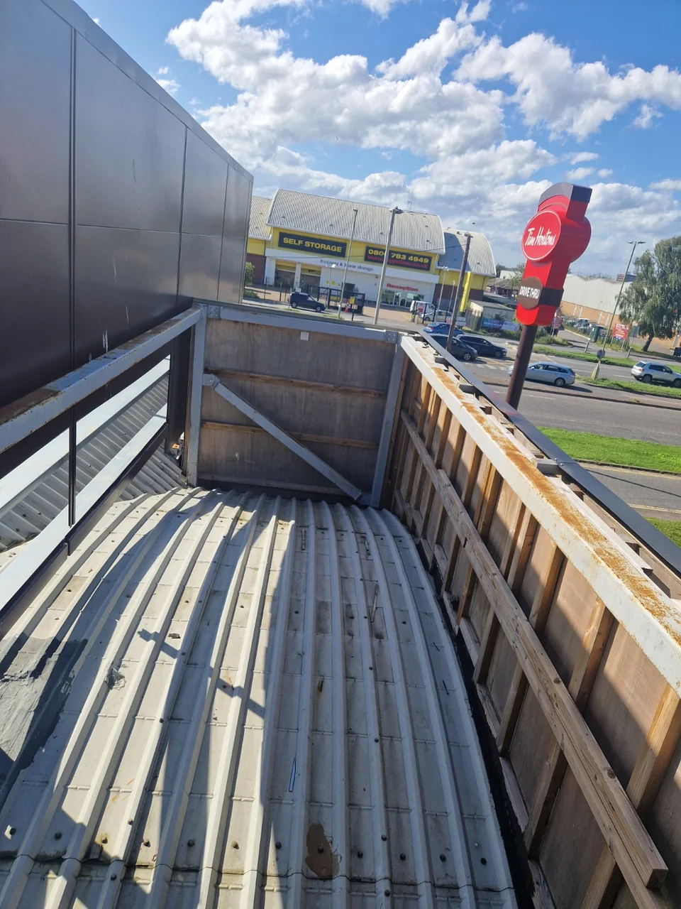 Metal roof covering and exposed perimeter structure with a Tim Hortons drive-through sign in the background.